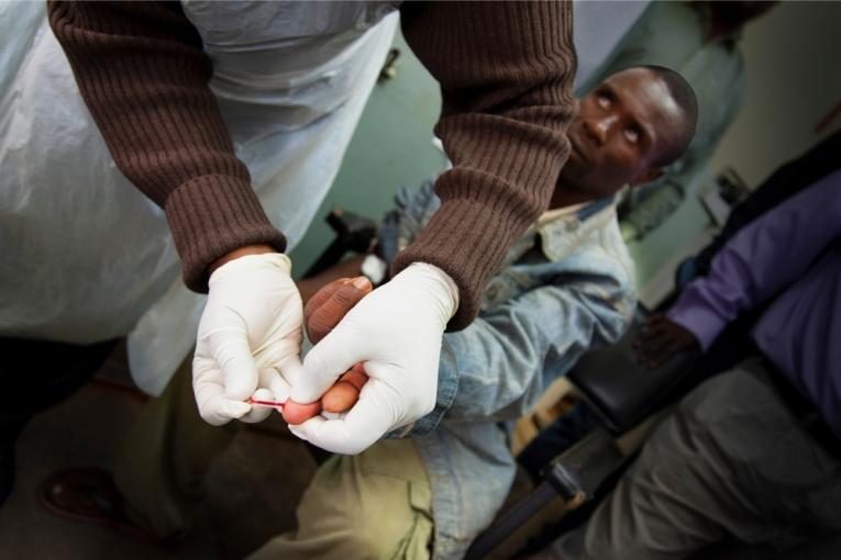 Un travailleur de santé pique le doigt d'un homme pour un étalonnage de tache de sang sur buvard (DBS) utilisé dans le test de charge virale. Une étude d'MSF au Malawi montre que les échantillons recueillis ainsi par les agents communautaires sont au