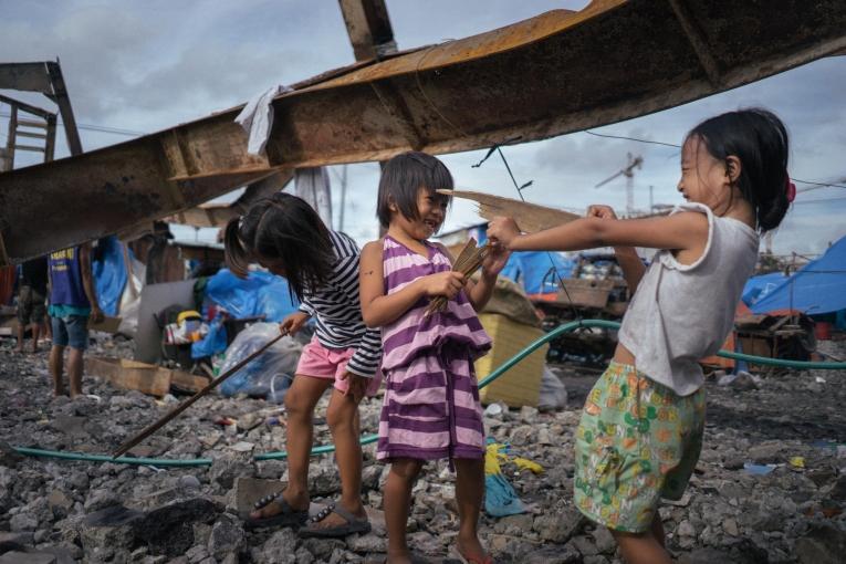 Des enfants jouent dans les décombres après la destruction de leur foyer par un incendie.
 © Hannah Reyes Morales