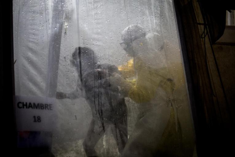 Un travailleur de santé MSF accompagne une patiente Ebola dans son lit du centre de traitement de Butembo. Novembre 2018. République démocratique du Congo.
 © John Wessels