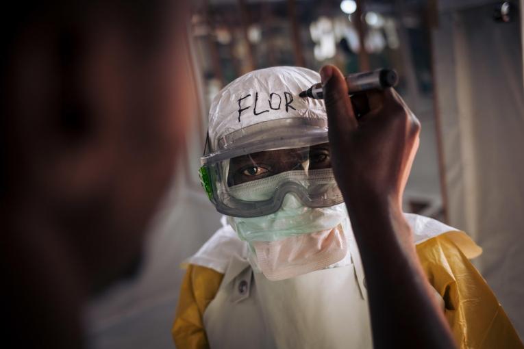 Un travailleur de santé MSF revêt son équipement de protection personnel avant d'entrer dans la zone à risque du centre de traitement Ebola. Leurs noms sont systématiquement écrits sur leur équipement. 2018. République démocratique du Congo.
 © Alexis Huguet