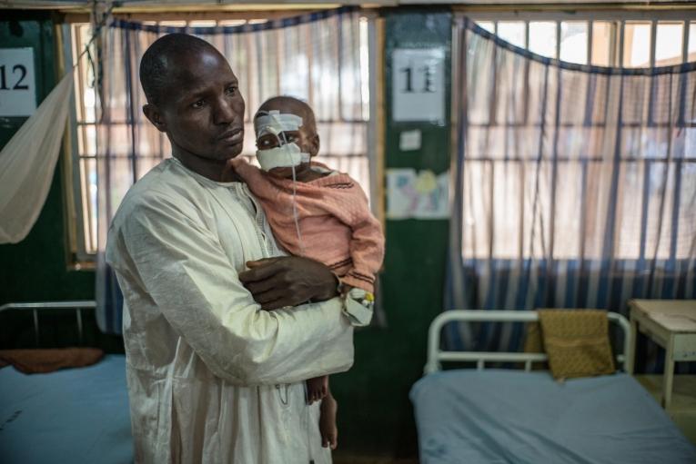 Un père et son fils à l'hôpital de Sokoto. Le petit garçon de deux ans souffrait de malnutrition due à sa difficulté à ingérer les aliments. Le noma a détruit une partie de son visage. Nigeria. 2016.

&nbsp;
 © Claire Jeantet - Fabrice Caterini/Inediz