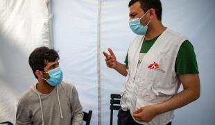 Elias Samim, traducteur MSF, discute avec un patient afghan à la clinique mobile avant sa vaccination contre le Covi-19.