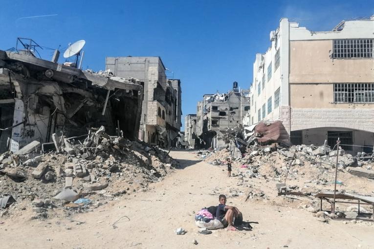 Un enfant assis au milieu de bâtiments détruits, Gaza, juin 2024. 