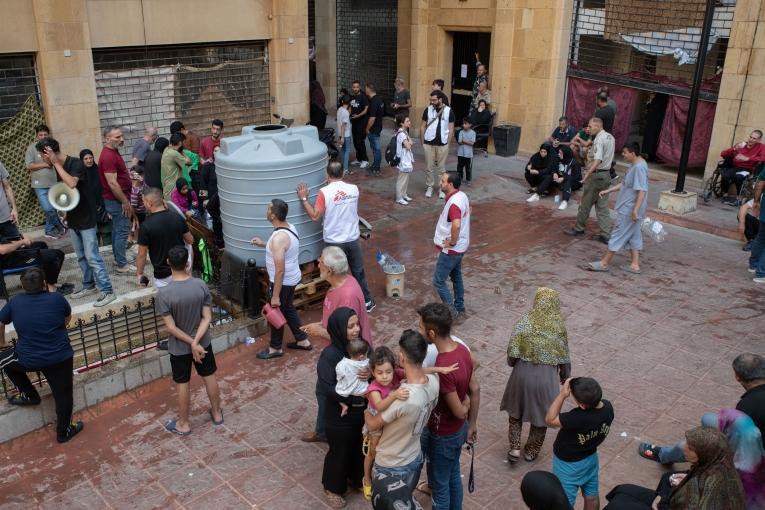 Dans le refuge d'Azarieh à Beyrouth, des familles déplacées se rassemblent autour d'un réservoir d'eau lors d'une distribution d'eau.