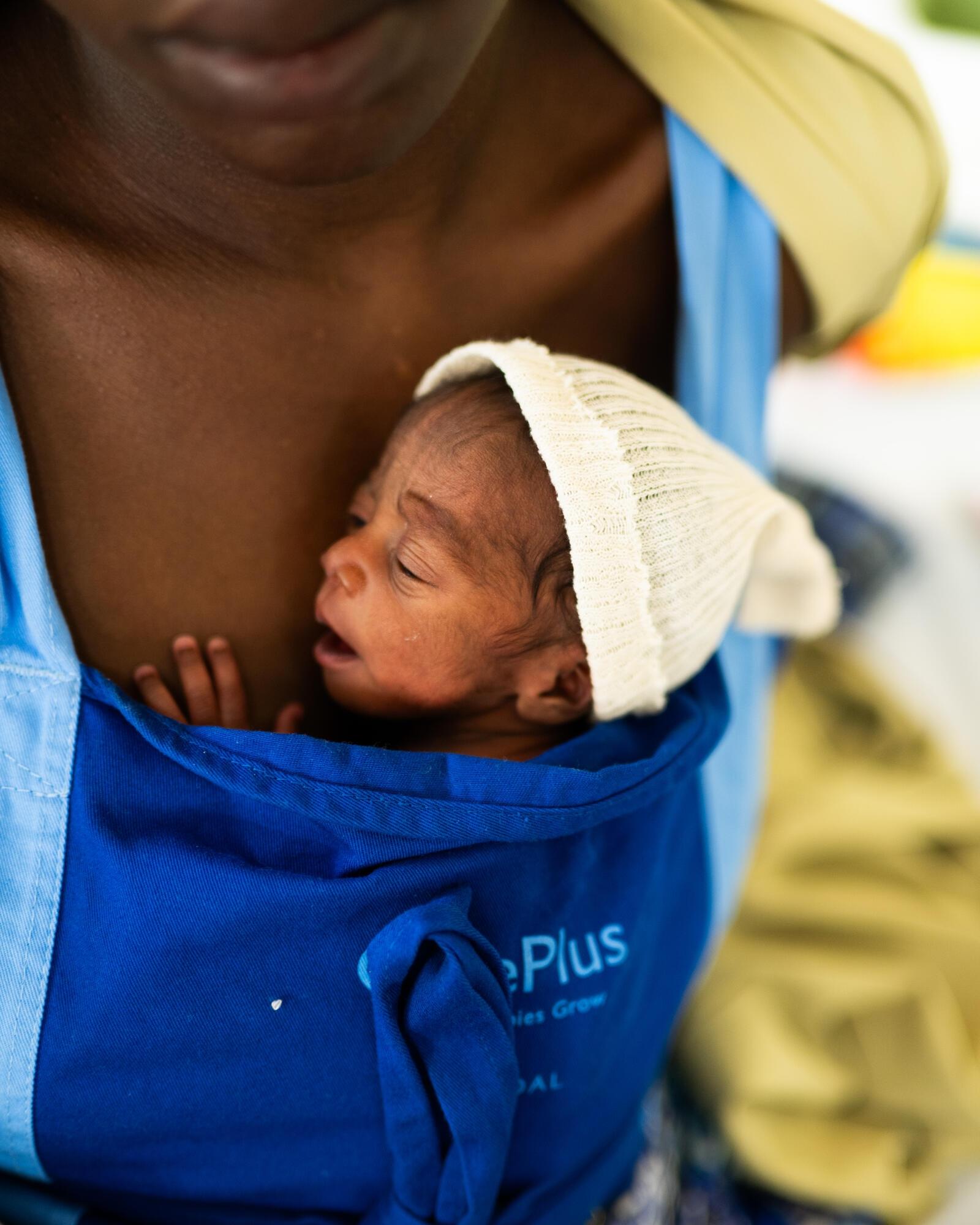 La même femme porte sa nièce dans un porte-bébé kanougourou. 