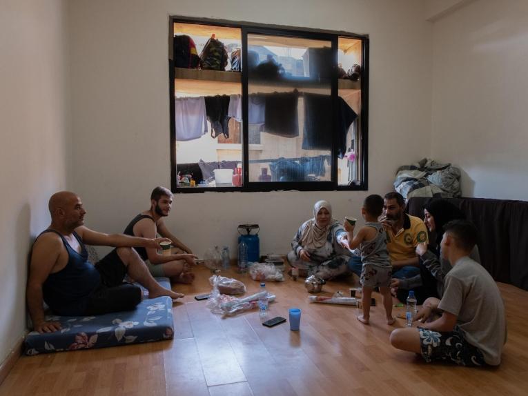 Une famille de personnes déplacées partage un repas dans leur chambre de l'abri d'Azarieh à Beyrouth.&nbsp;
 © Antoni Lallican/Hans Lucas