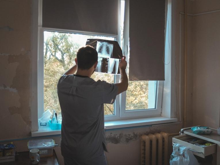 Le physiothérapeute MSF Oleksii Taranenko examine les radios d'un patient avant une séance thérapeutique. Octobre 2024.
 © Anhelina Shchors/MSF