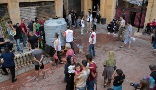 Dans le refuge d'Azarieh à Beyrouth, des familles déplacées se rassemblent autour d'un réservoir d'eau lors d'une distribution d'eau.