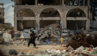 Dans le quartier de Shujaeyya, rue Bagdad, à Gaza, une femme ramène son enfant à la maison à travers les décombres. ©Motassem Abu Aser 