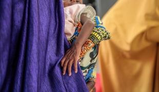 Fatima Isyaka (droite) place son bébé sur une balance afin de le peser. L’enfant souffre de malnutrition aiguë sévère, il est pris en charge au centre nutritionnel de MSF, État de Katsina, Nigeria, juin 2022. 