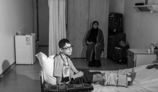 Abdul Rahman sur son lit dans l'hôpital MSF d'Amman, avec sa mère. Août 2024. Jordanie.
