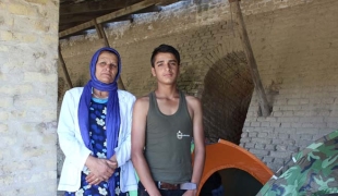 Haseeb 13 ans et sa mère Zubida debout au milieu des tentes abandonnées des réfugiés dans l’ancienne briqueterie de Subotica en Serbie.