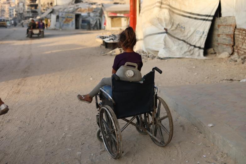 Une enfant près d'un fauteuil roulant qu'elle utilise pour transporter des jerricans d'eau, dans la ville de Gaza, en raison de la destruction systématique des infrastructures hydrauliques par Israël.