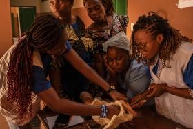 Victoire Irène Sossou, 26 ans, sage-femme avec MSF (debout à droite) forme d’autres sages-femmes et aides-soignantes d'Etat au centre de santé de Toviklin, Benin, le 16 janvier 2025. ©Adrienne Surprenant / MYOP